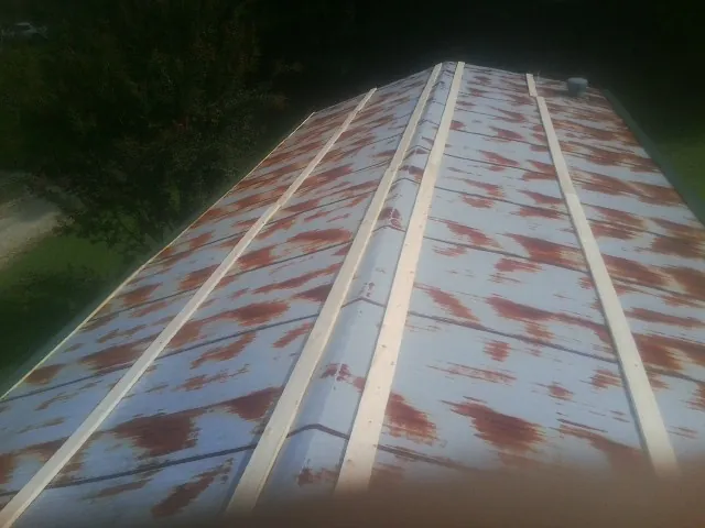 Rusted metal roof panels with new wood purlins before replacement — Storm Damage Roof Repair in Great Lakes by Roofing Brothers