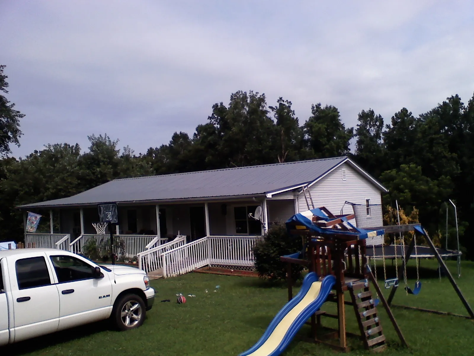 Dark metal roof on a country home with a full length front porch in Great Lakes