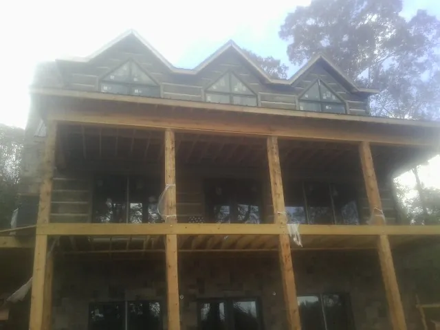 Dormers and porch framing on a large log home under construction — Roof Coating work by our crew in Great Lakes