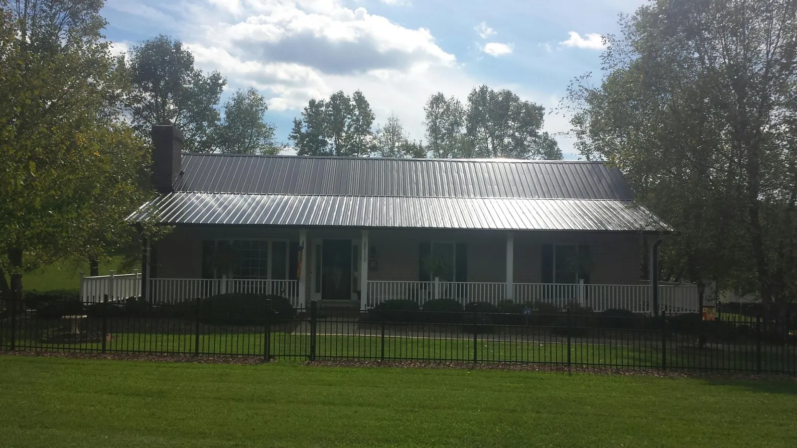 Gray metal roof on a brick ranch with a full width front porch — Gutter Guard Installation work by our crew in Great Lakes