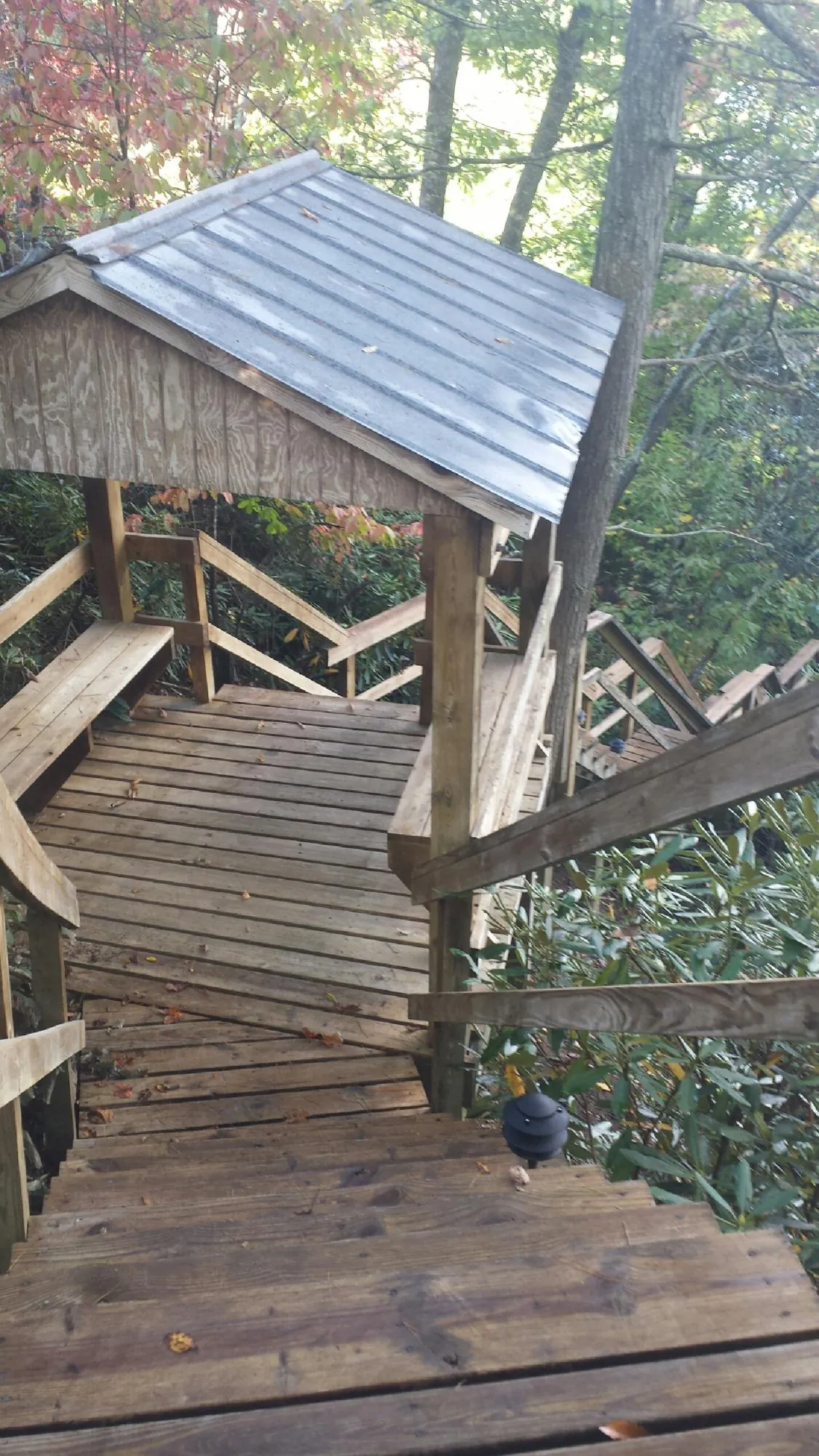 Metal roofed shelter over wooden steps on a wooded walkway — Skylight Repair & Installation work by our crew in Great Lakes
